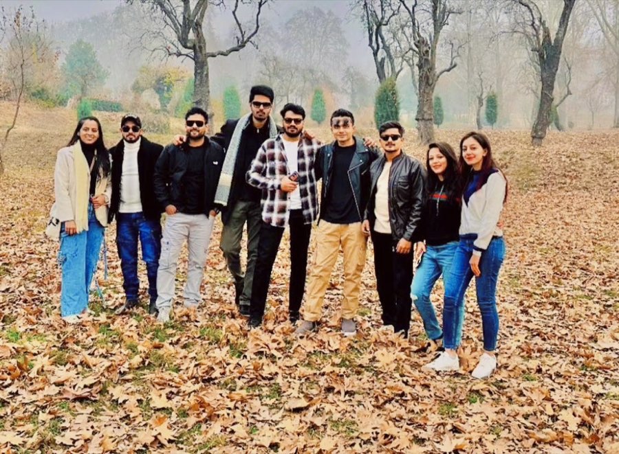 Nine travellers posing on a carpet of autumn chinar leaves